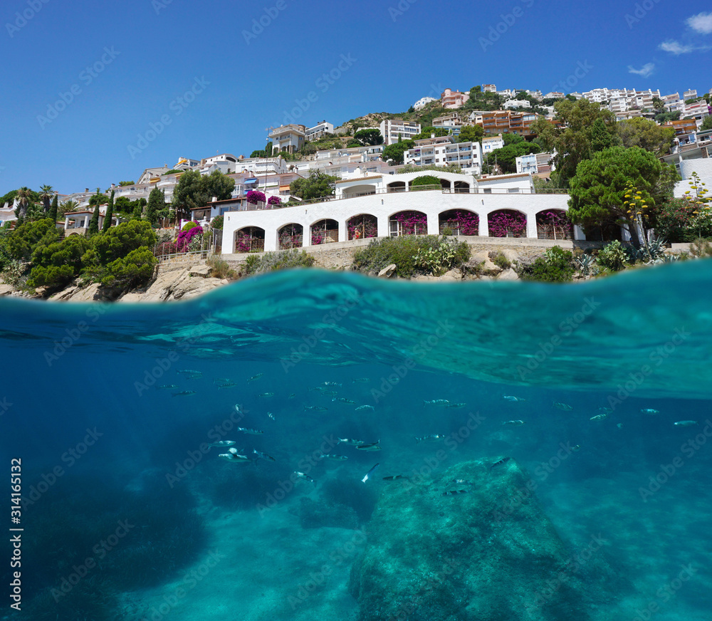 Spain, buildings on the coastline with mullets fish underwater, Mediterranean sea, split view over and under water surface, Costa Brava, Catalonia, Roses, Canyelles Petites