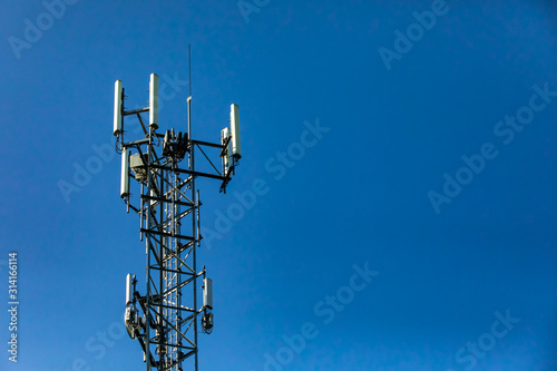 Fototapeta Naklejka Na Ścianę i Meble -  Details of multiple antenna atop a steel lattice tower against a blue sky with copy space on right. Mobile data and technology transmission exchange