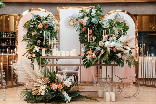 Wedding table serving. Wedding luxury decor. Wedding presidium for the newlyweds. Beautiful decor with pastel roses, candles and greenery. Indoors