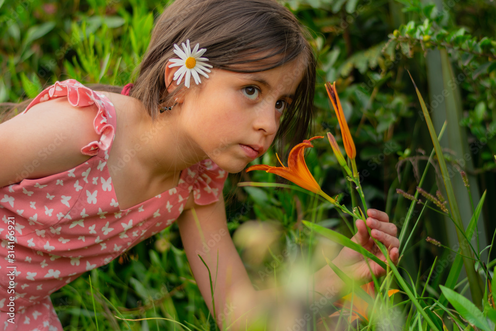 long-haired Colombian girl smells the flowers of the garden in the spring long-haired Colombian girl smells the flowers of the garden in the spring