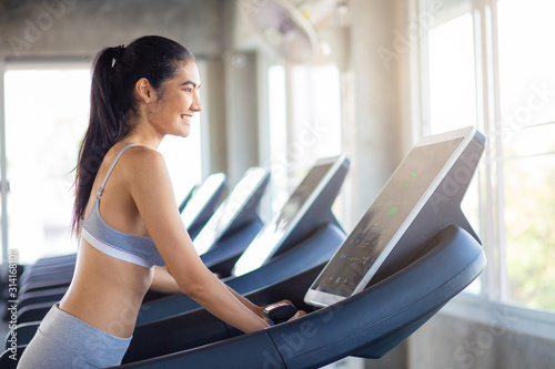 Attractive asian sport women running on treadmil with friend in sport gym
