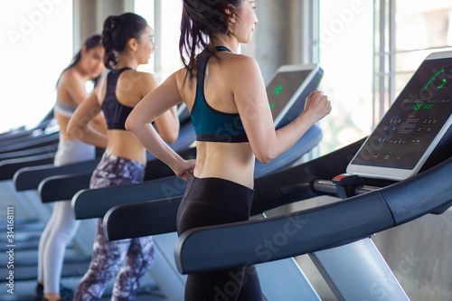 Attractive asian sport women running on treadmil with friend in sport gym