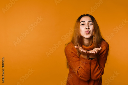Charming girl blowing air kiss on the orange banner background © IVASHstudio