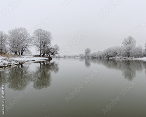 Beautiful winter scene with calm river and frozen trees in Arad, Romania