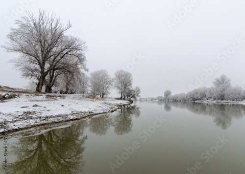 Beautiful winter scene with calm river and frozen trees in Arad, Romania