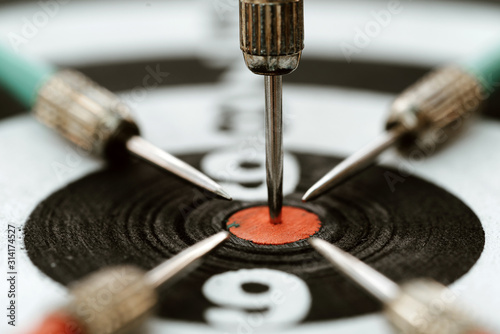 Close-up dart arrow hitting target centre dartboard background. Business targeting and focus concept.