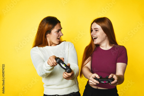 Two young girls sre playing a game standing on the yellow banner background