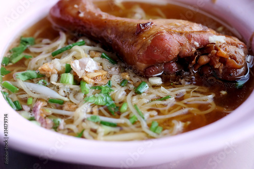 Braised Chicken Leg Noodle in plastic bowl and space for write wording, popular street food sold in market and restaurant, danger from dirty, dust and unhealthy material.