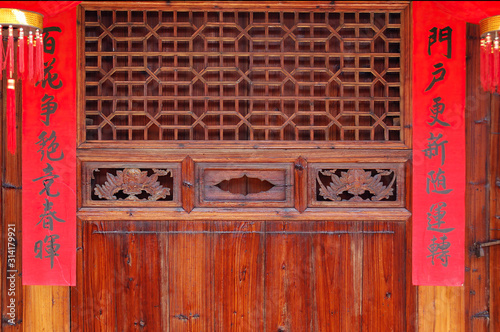 The old traditional style wood carving door with Spring festival couplets during Chinese new year.The text on scrolls  means Hundreds of flowers in bloom in springtime and Good luck will come to home