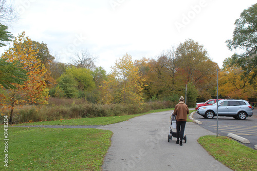 Woman with a stroller walking on a trail at McDowell Grove Forest Preserve in Naperville, Illinois in autumn © John