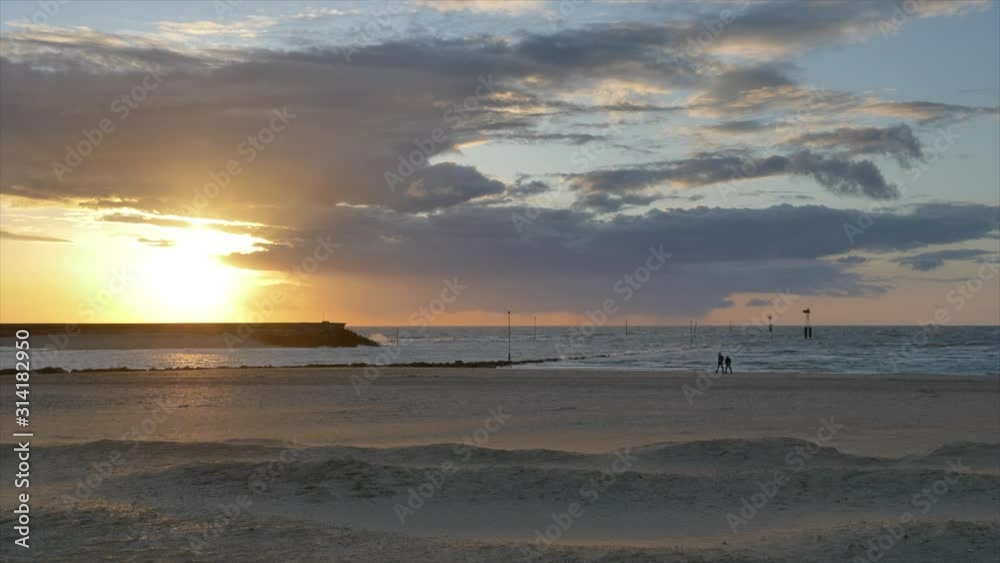 Beautiful beach landscape in golden hour, silhouettes of people walking. Static Beautiful beach landscape in golden hour, silhouettes of people walking. Static