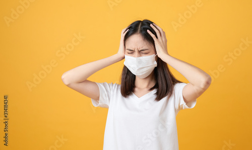 Asian women wear masks to protect disease and the headache from a virus on orange background.