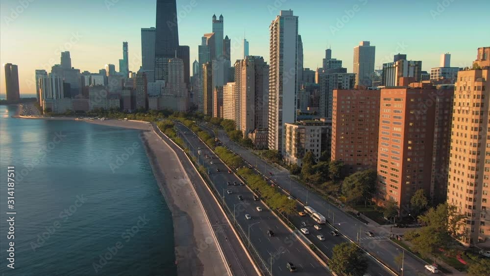 Aerial: Morning rush hour traffic on North Lake Shore Drive alongside Lake Michigan at sunrise. In the background is the Chicago city skyline.  Chicago, Illinois, USA.