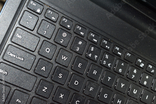 Side photo of a laptop keyboard showing brushed black surface. Technology concept. selective focus.