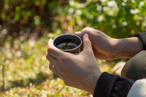 drinking Dripping Coffee or Filter coffee in the mountain and sunrise at camp with nature, Closed up at hand and a cup of dripping coffee in the afternoon or moring with green nature Background photo