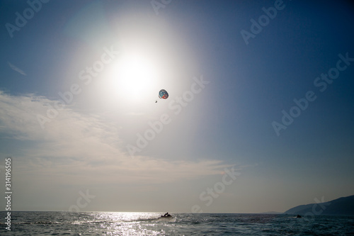 Jet ski and skydiver in the sky over the sea. Summer outdoor activities on the water.