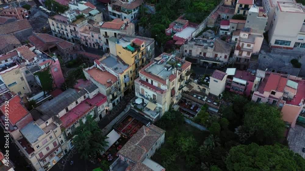Aerial shot of the medieval buildings in Sicilian commune; Taormina, Italy. Camera goes down and tilts up to reveal a mountain above the city Aerial shot of the medieval buildings in Sicilian commune; Taormina, Italy. Camera goes down and tilts up to reveal a mountain above the city