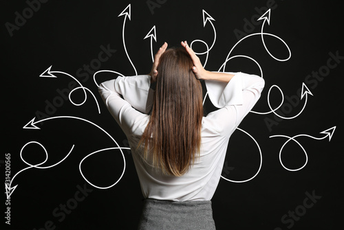 Stressed businesswoman and many arrows on dark background. Concept of choice