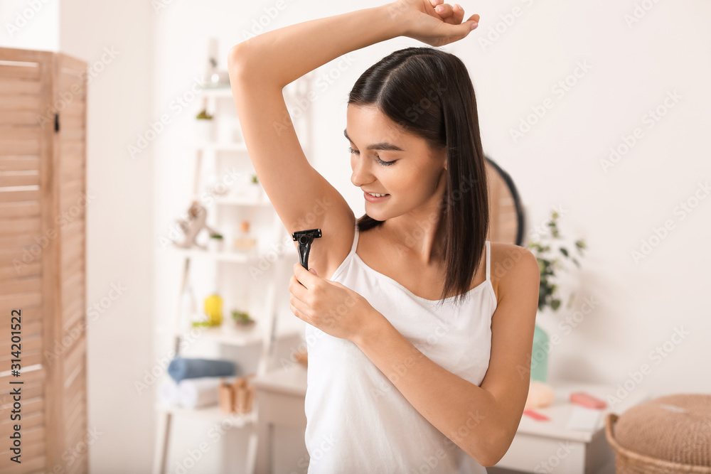 Beautiful young woman shaving armpits in bathroom Beautiful young woman shaving armpits in bathroom