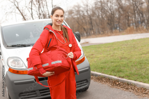Female paramedic with bag near ambulance car outdoors © Pixel-Shot