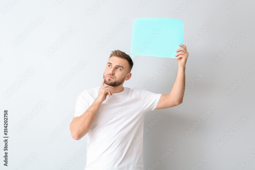 Thoughtful young man with blank speech bubble on light background Thoughtful young man with blank speech bubble on light background