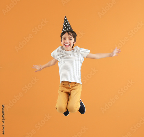 Photography Jumping little boy with party hat on color background