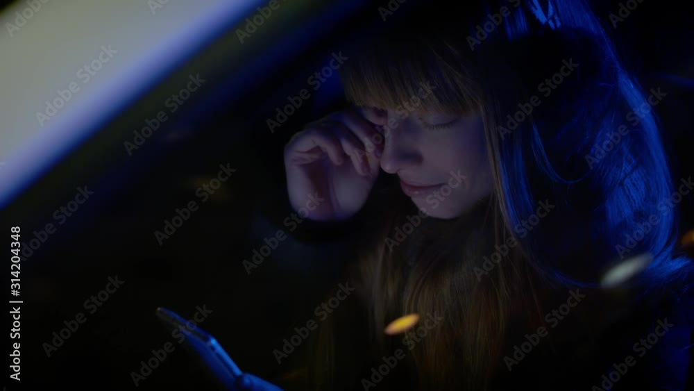 Crying woman seated in car wiping a tear