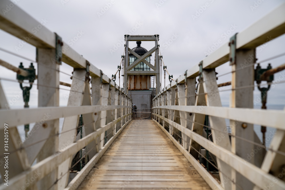 Small white suspension bridge foot path leading to lighthouse
