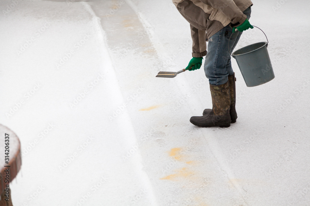 Worker sprinkles slippery track in yard with dry sand Worker sprinkles slippery track in yard with dry sand