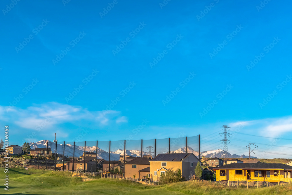 Homes and golf course with scenic nature background under vibrant blue sky