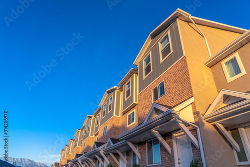 Exterior of townhomes viewed against vibrant blue sky and snow capped mountain