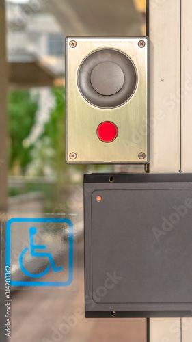 Vertical Glass door of a modern building with security key card reader and handicap sign photo