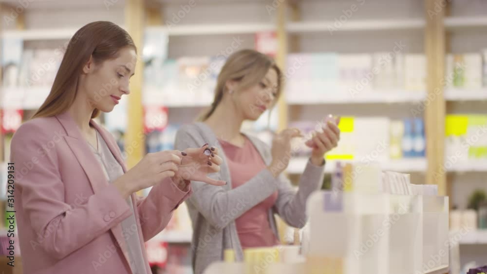 Tracking shot of attractive young women looking at makeup products in cosmetic store Tracking shot of attractive young women looking at makeup products in cosmetic store