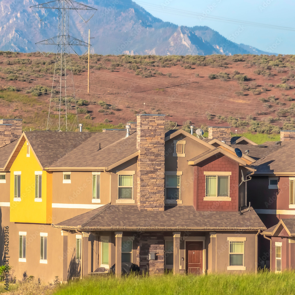 Square frame Exterior of homes in the suburb with power lines mountain and sky background