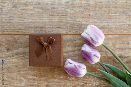 Gift box with tulip flowers on the wooden background.