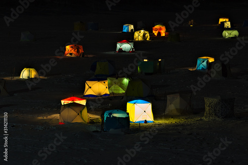 Winter fishing. Tourist campground for fishermen at night. Illuminous tents on the ice of a frozen winter lake. Urals, Rassia photo