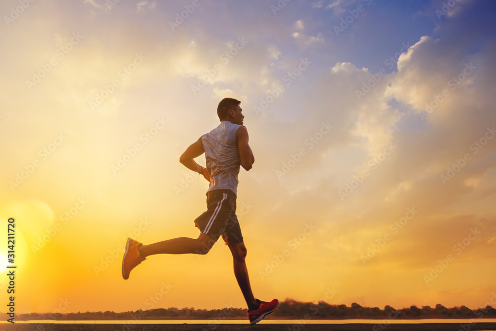 Silhouette of man running sprinting on road. Fit male fitness runner during outdoor workout with sunset background