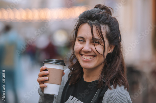young pretty woman at city street drinking coffee from disposable cup