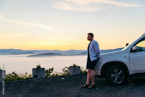 man looking at sunrise in mountains suv car near it © phpetrunina14