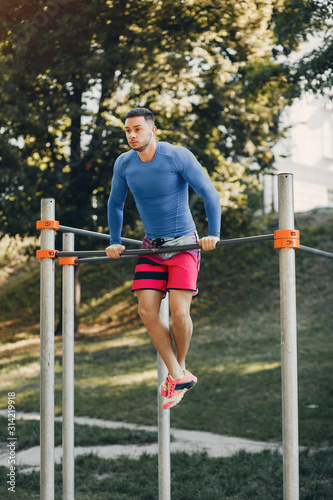 Man training. Guy in a sports clothes. Male in a summer park