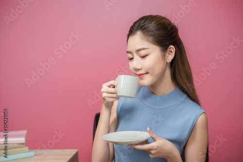 portrait beauty asia woman smiling holding cup with right hand and pink wall background copy space.