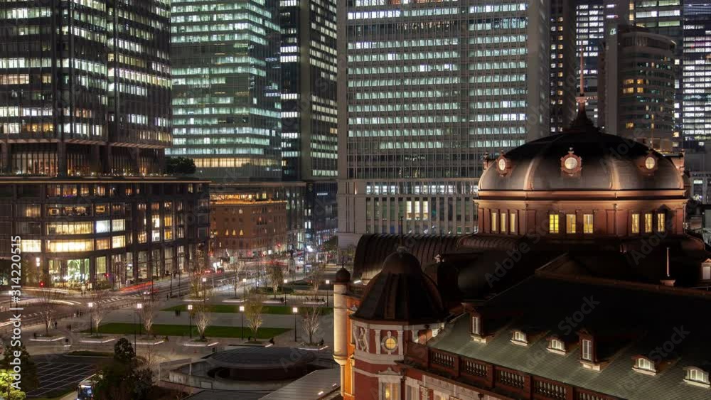 Timelapse famous Tokyo Railway Station historical terminal with large dome at pictorial square against illuminated skyscrapers at night zoom out