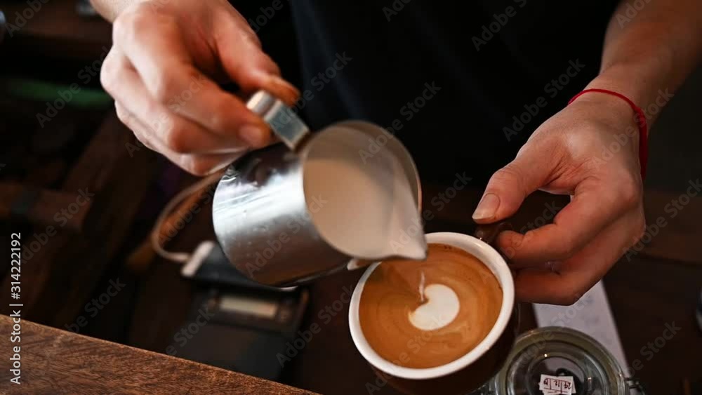 Cropped shot of Barista hand trying to pouring steamed milk to hot coffee to making latte art. A latte is a coffee drink made with espresso and steamed milk. Cropped shot of Barista hand trying to pouring steamed milk to hot coffee to making latte art. A latte is a coffee drink made with espresso and steamed milk.
