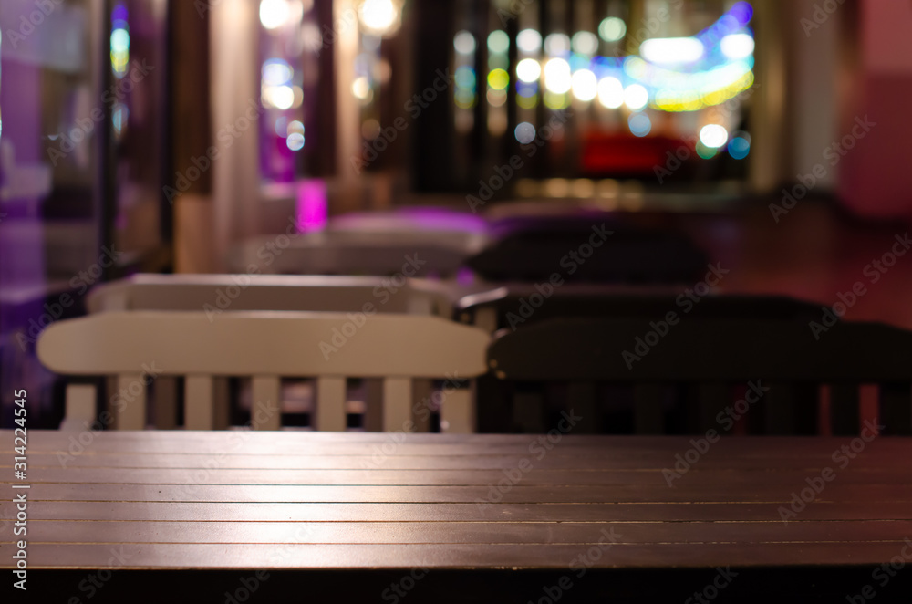 Image of wooden table in front of abstract blurred restaurant lights background in Christmas decoration.