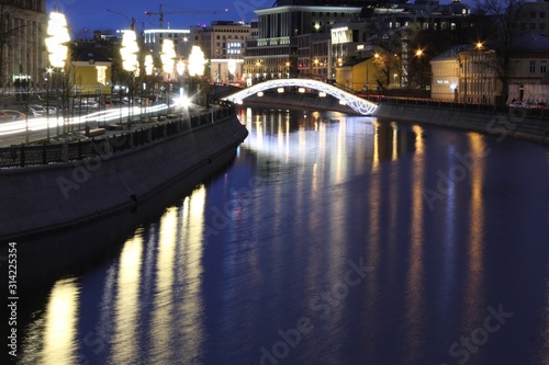 Illuminated bridge over the river in Moscow in the evening in winter