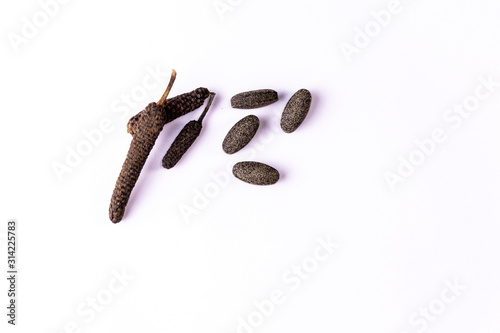 long pepper or piper longum and brown ayurvedic pills spread on white background. Ayurvedic medicines concept photo