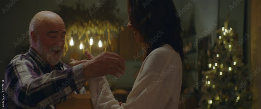 Adult daughter giving elderly father a hug as multi generation family celebrate Christmas at parents home. Shot on ARRI Alexa Mini with Cooke 2x Anamorphic lenses. 4K UHD RAW Graded footage Adult daughter giving elderly father a hug as multi generation family celebrate Christmas at parents home. Shot on ARRI Alexa Mini with Cooke 2x Anamorphic lenses. 4K UHD RAW Graded footage