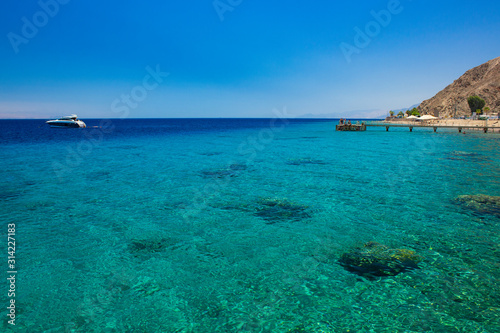 summer time vacation season tropic nature landscape view Gulf of Aqaba Red sea bay waters coast coral reefs pier with relaxation people and yacht background horizon line and copy space for your text