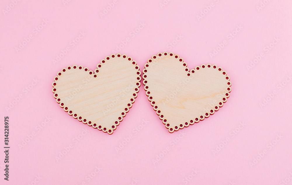 Two laced wooden hearts on a pink background. Symbol of love, fidelity, passion. Copy space. 