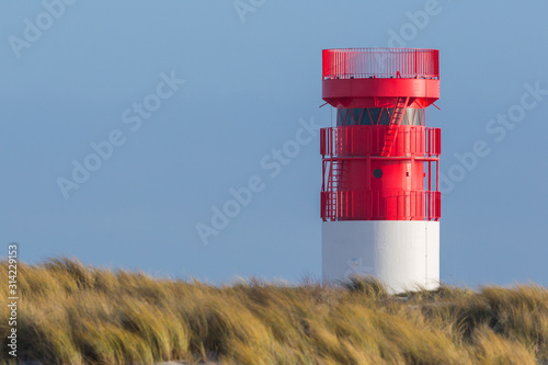 red lighthouse on Helgoland Duene island, blue sky, golden grass